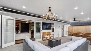 A spacious living area with a large sofa, two wooden chairs, a coffee table, and a ceiling fan. - Cottage by the Harbor (Dana Point)