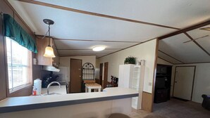 A compact kitchen with a bar area, a sink, and two stools.