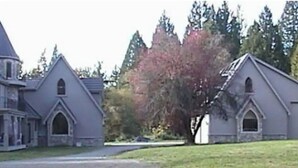 Un edificio grande e histórico con una torre destacada y varios ventanales arqueados.