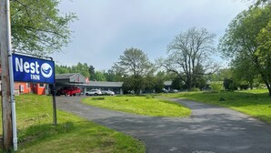 Segnaletica di Nest Inn, un'area di parcheggio e un edificio con facciata rossa.