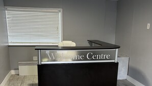 Una reception con un cartello che indica 'Welcome Centre', una finestra con persiane e un pavimento piastrellato.