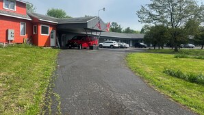 Un edificio con facciata rossa e area di parcheggio coperta.