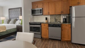 Una habitación de hotel moderna con kitchenette, que incluye microondas, estufa, lavavajillas y refrigerador.