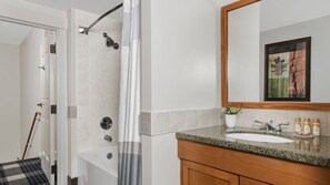Un baño con ducha, lavamanos y espejo.