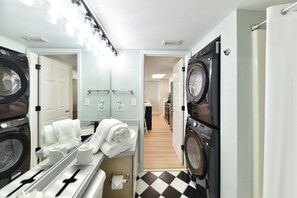 Een wasserette in een hotel met twee wasmachines, een droogrek en een spiegel.