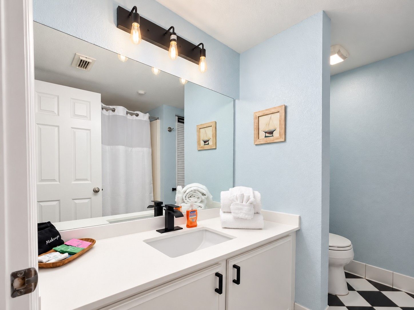 A bathroom with a white sink, a mirror, a towel rack, and a toilet.