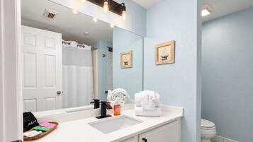 A bathroom with a white sink, a mirror, a towel rack, and a toilet.