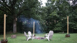 A backyard with a fire pit, string lights, and Adirondack chairs. - Deer Meadow-Devil`s Bathtub/Natural Tunnel (Duffield)