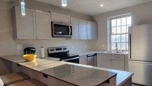 A modern kitchen with a central island, stainless steel appliances, and light-colored cabinetry. - New Modern 2 BR in Excellent Location (201) (Maryville)