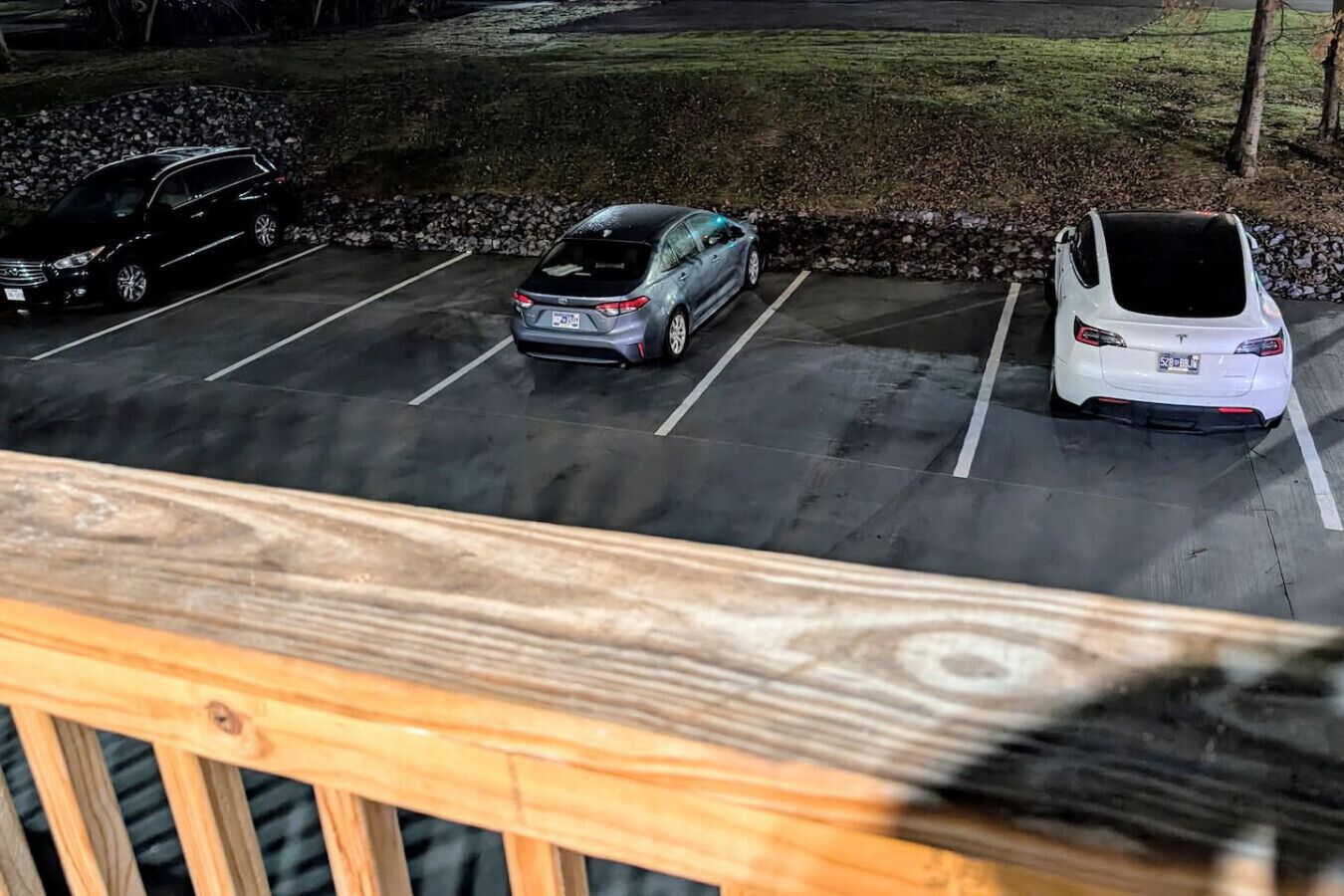 Um parque de estacionamento com três carros estacionados em lugares demarcados.