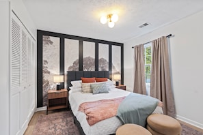A bedroom with a large bed, two bedside tables, a headboard, and a window with curtains. - Fayetteville Gem -Pet friendly / near Trilith Studios  (Fayetteville)