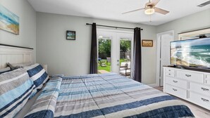 A bedroom with a bed, a television, a ceiling fan, and a view of the outdoors. - “Big Jer’s” with a Cement Pond (Houston)