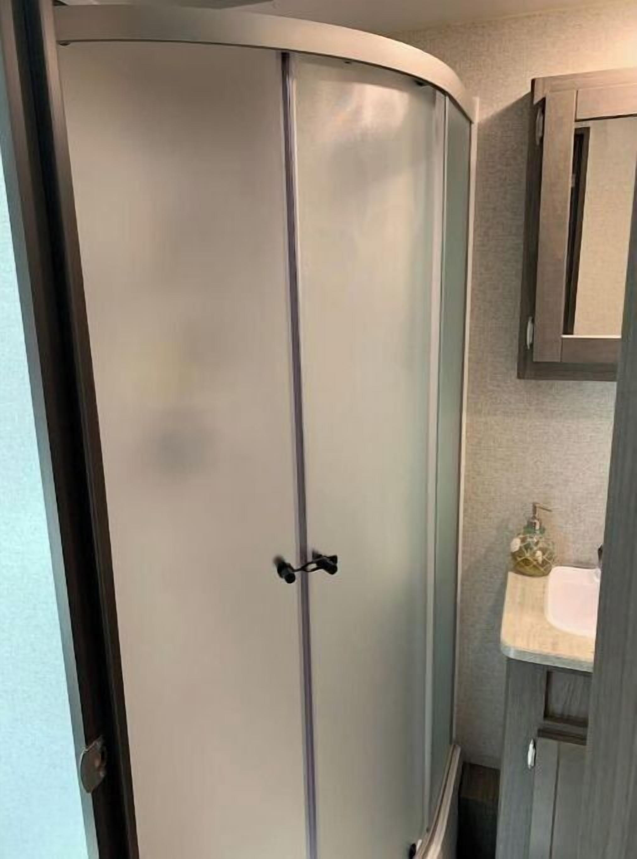 Ein Badezimmer mit Duschkabine, Waschbecken und Schrank.