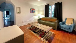 Un salon avec un canapé, un fauteuil bleu, une table basse et un tapis.