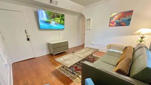 Un salon équipé d’un téléviseur à écran plat, d’un canapé, d’une table basse et d’un tapis.