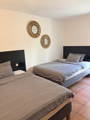 Een kamer met twee bedden, elk met hoofdeinde en kussen. Er zijn twee spiegels aan de muur bevestigd.