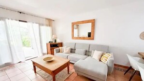 A living room with a sofa, a wooden coffee table, a small side table, and a mirror on the wall.