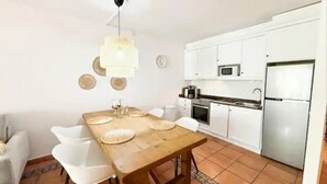 A compact kitchen with white cabinets, a microwave, and a refrigerator.