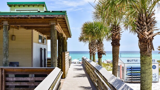 A wooden pier leading to a beach with palm trees and a view of the ocean. - Private Pool, Carriage House, and Near the Beach (Destin)