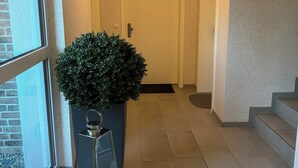 A hallway with a potted plant, a glass display case with candles, and a door at the end. - Kleine Auszeit - Scharbeutz **incl. Parking | WiFi | Terrace with beach chair** (Scharbeutz)
