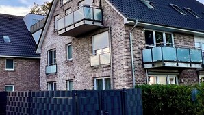 A multi-story residential building with a brick facade, large windows, and a balcony. - Kleine Auszeit - Scharbeutz **incl. Parking | WiFi | Terrace with beach chair** (Scharbeutz)