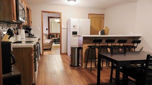 Une cuisine de taille réduite, dotée de meubles en bois, d’un réfrigérateur blanc et d’un coin repas avec une table et des chaises.