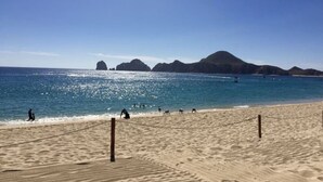 A sandy beach with a clear blue sky and calm sea.