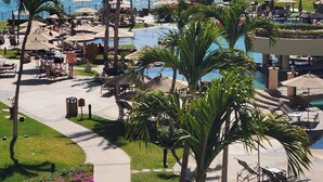 A resort with a pool area, lounge chairs, and a view of the sea.