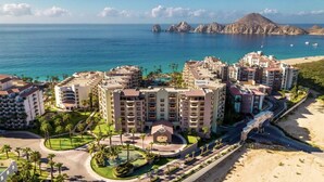 A coastal hotel complex with multiple buildings, a central courtyard, and a beach view.