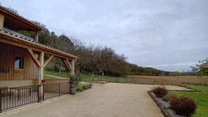 A wooden building with a covered porch and a gravel driveway leading to a swing set.