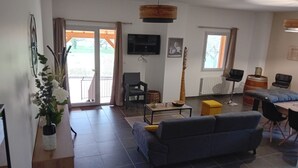 A living room with a sofa, a coffee table, a TV, and a dining area with chairs.