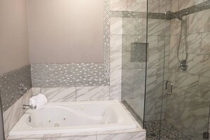 A bathroom with a freestanding bathtub, a glass-enclosed shower, and a tiled backsplash.
