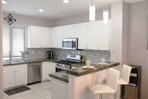 A modern kitchen with white cabinetry, a stainless steel stove, and a microwave.
