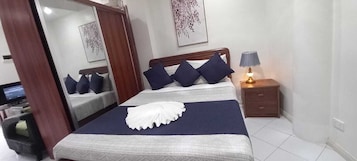Quarto bem organizado com cama, mesa de cabeceira, abajur e espelho.