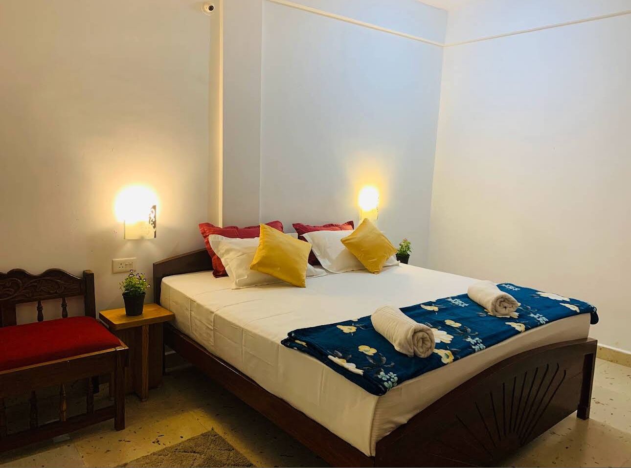 Un dormitorio ordenado con cama, mesitas de noche y una silla.
