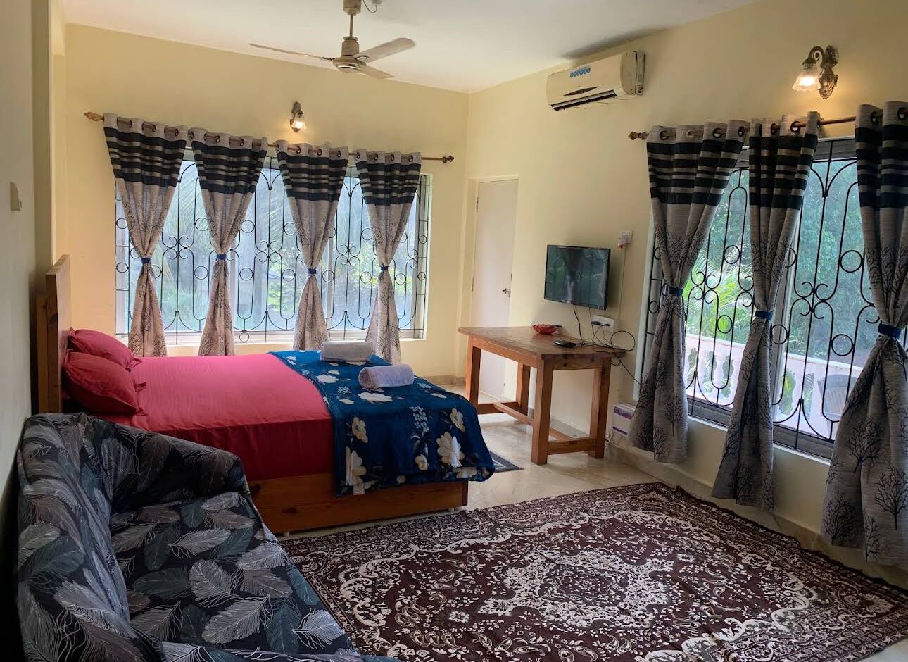 Un dormitorio con cama, una silla, una mesa y cortinas.