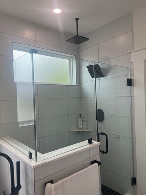Un bagno moderno con cabina doccia in vetro, un mobile lavabo bianco e un portasciugamani.