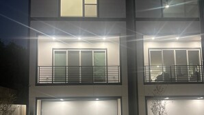 Et moderne hus med to etager, garage, oplyste vinduer og en velholdt græsplæne.