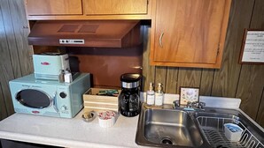 Een praktische keuken met houten kastjes, een ingebouwde oven, een koffiezetapparaat en een spoelbak met een afdruiprek.