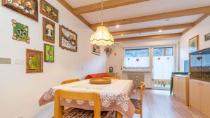 Un comedor con una mesa y sillas de madera, una lámpara colgante y varias obras de arte enmarcadas en las paredes.