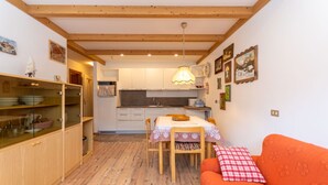 Una cocina acogedora con armarios de madera, una mesa de comedor con sillas y una lámpara colgante.