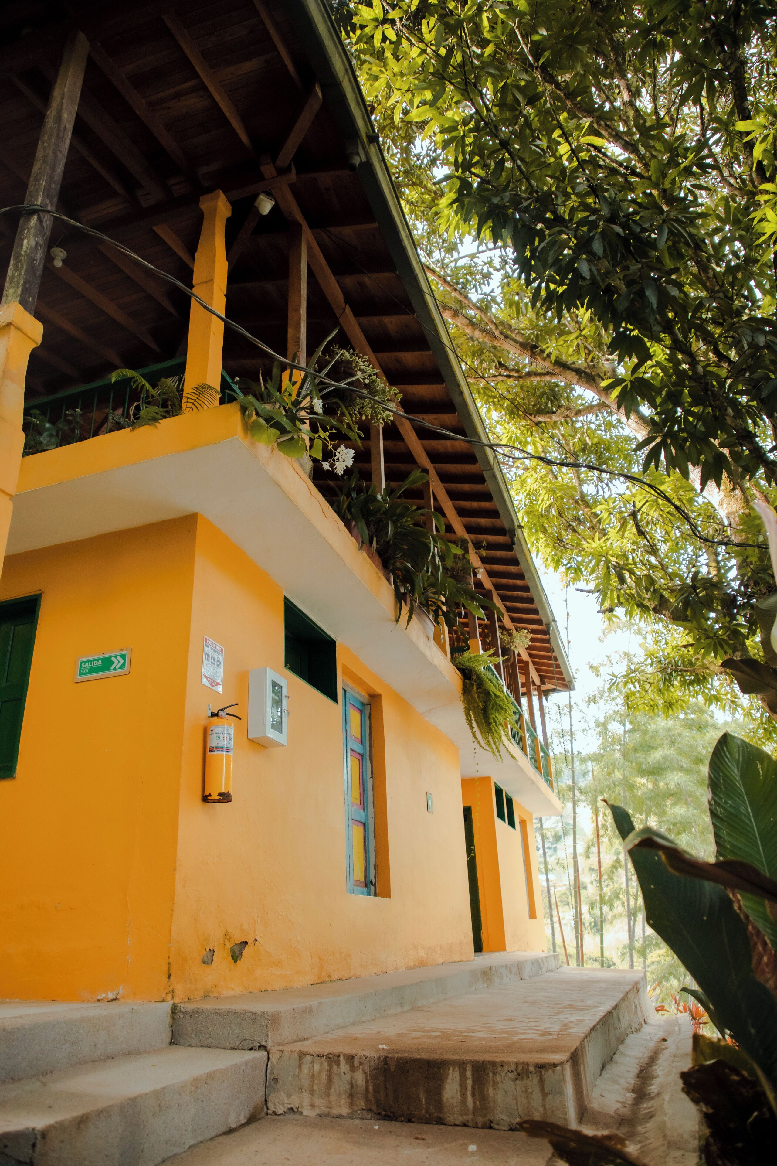 Un bâtiment jaune doté d’un balcon, d’un escalier et d’une porte verte.