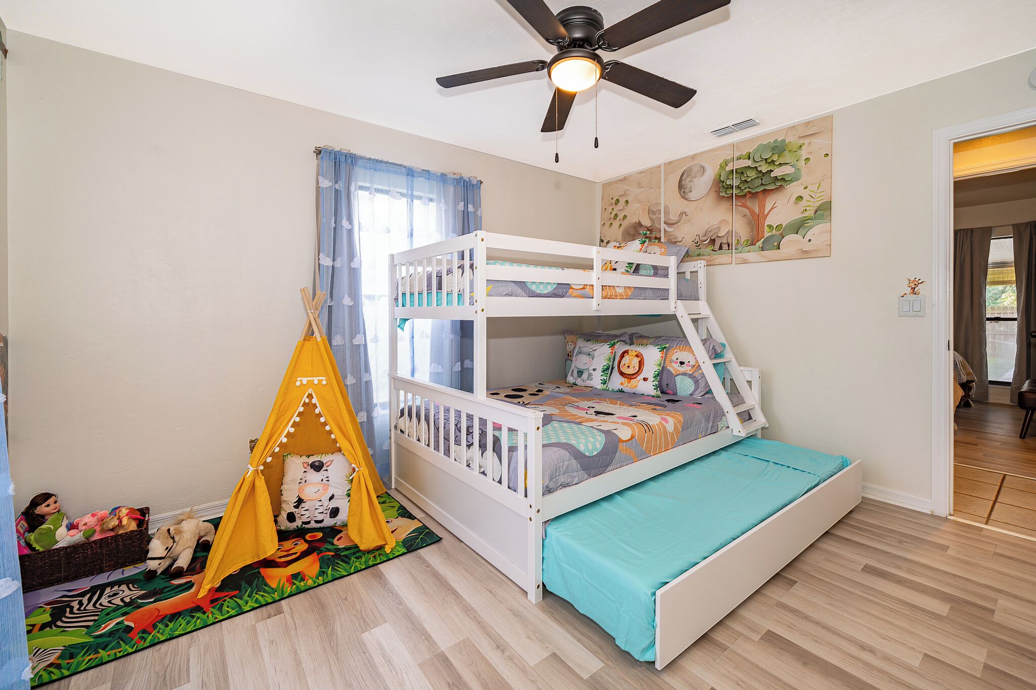 A child’s room with bunk beds, a ceiling fan, and a tent-like play area.