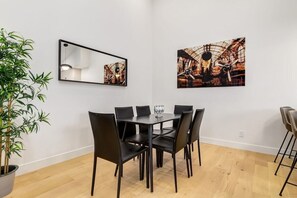 A dining area with a table and chairs, a potted plant, and two framed artworks on the wall. - Long Stays, Fenced Yard, Free Parking & King Bed (Calgary)