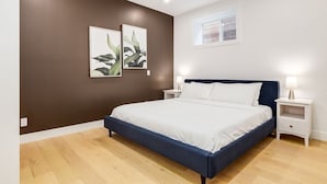 Une chambre à coucher avec un grand lit, deux tables de chevet et des œuvres d’art accrochées au mur.