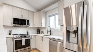 Une cuisine moderne équipée d’appareils électroménagers en acier inoxydable, notamment un four à micro-ondes, un four et un réfrigérateur.