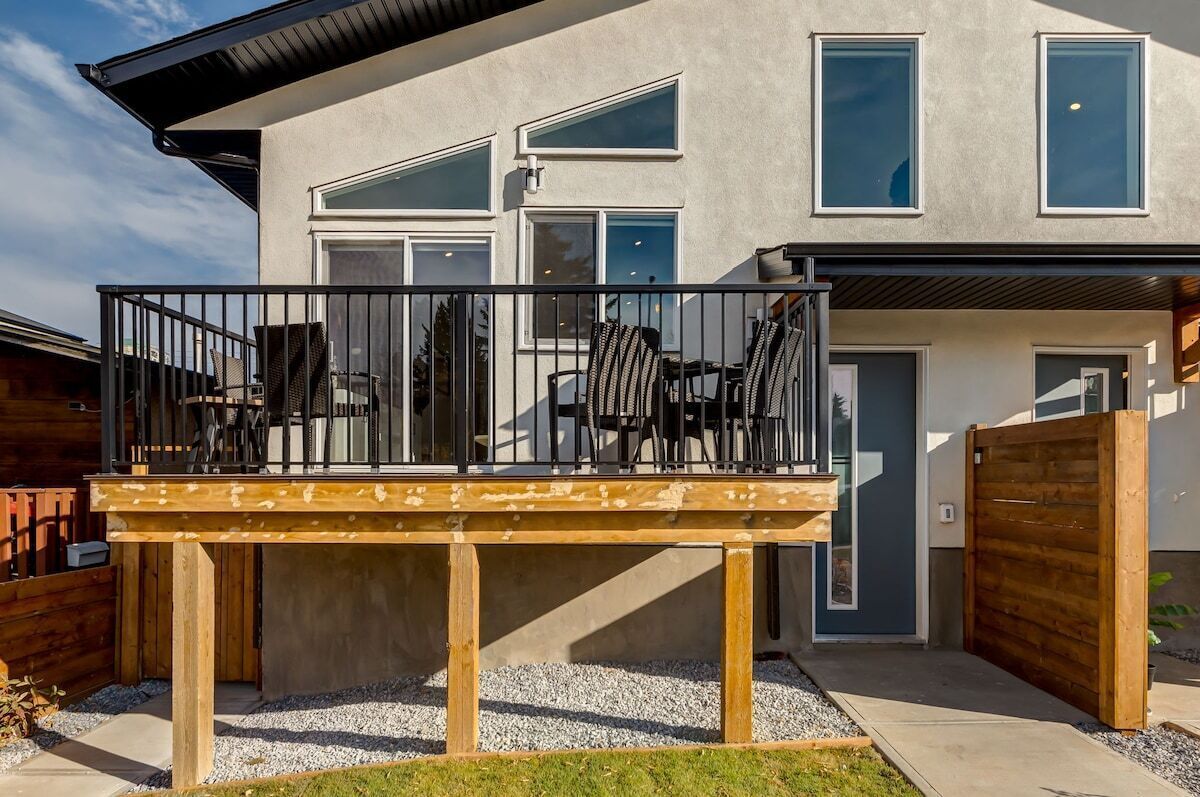 Ein modernes Haus mit Balkon, Holzterrasse und geschlossenem Eingang.