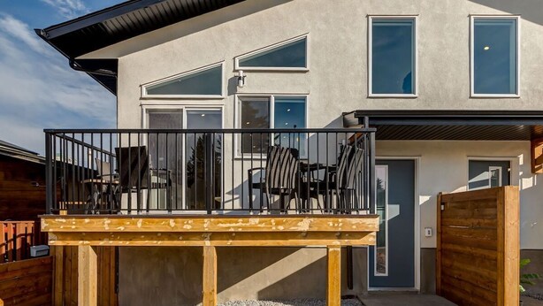 Une maison moderne dotée d’un balcon, d’une terrasse en bois et d’une entrée sécurisée par un portail.