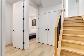 A room with a bed, a white wardrobe, and a wooden staircase.