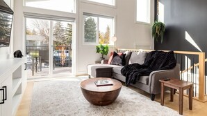 A modern living room with a sofa, coffee table, and a large window. - Guest Favourite, King B, Family Friendly (Calgary)